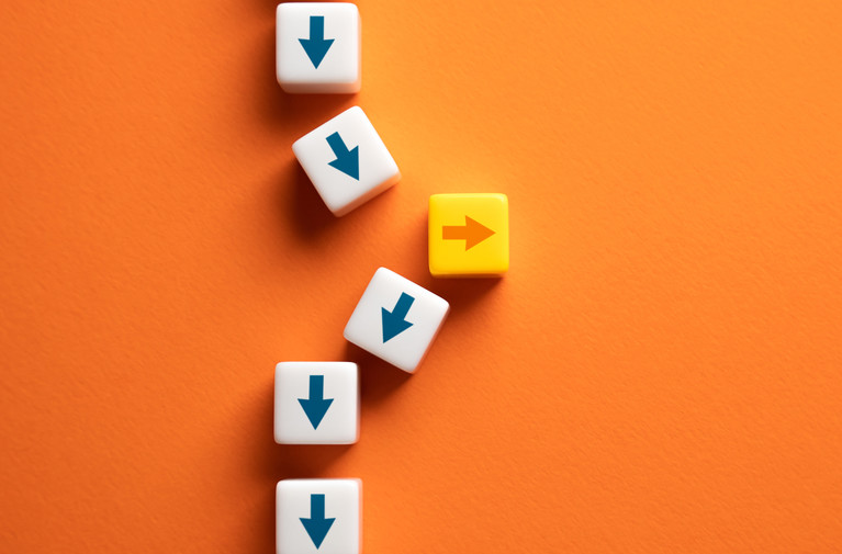 White dice with blue downward arrows and a yellow die with an orange right arrow arranged diagonally on an orange background.
